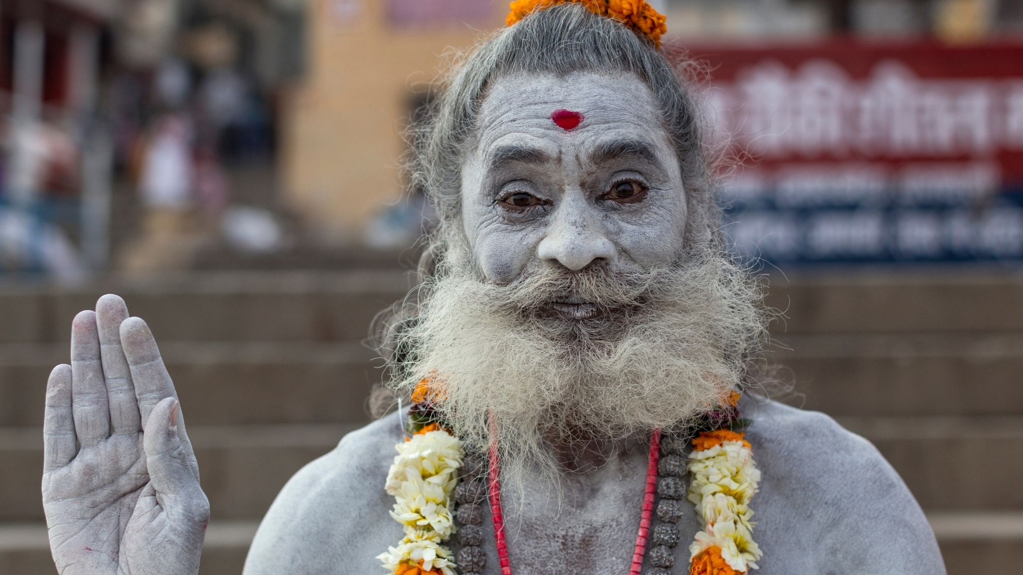 Um sadhu coberto de cinzas e guirlandas de flores em Varanasi