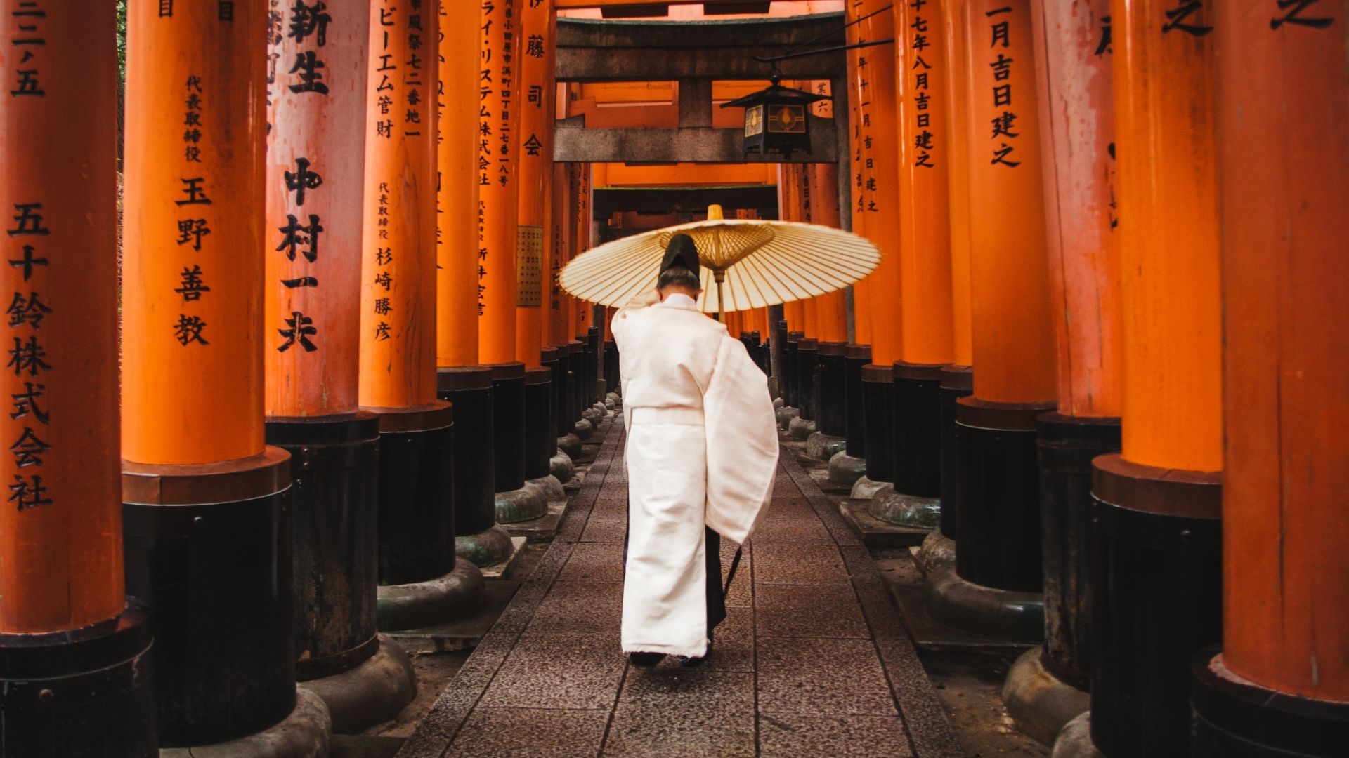 Les torii vermillon de Fushimi Inari à Kyoto, avec une personne en kimono blanc