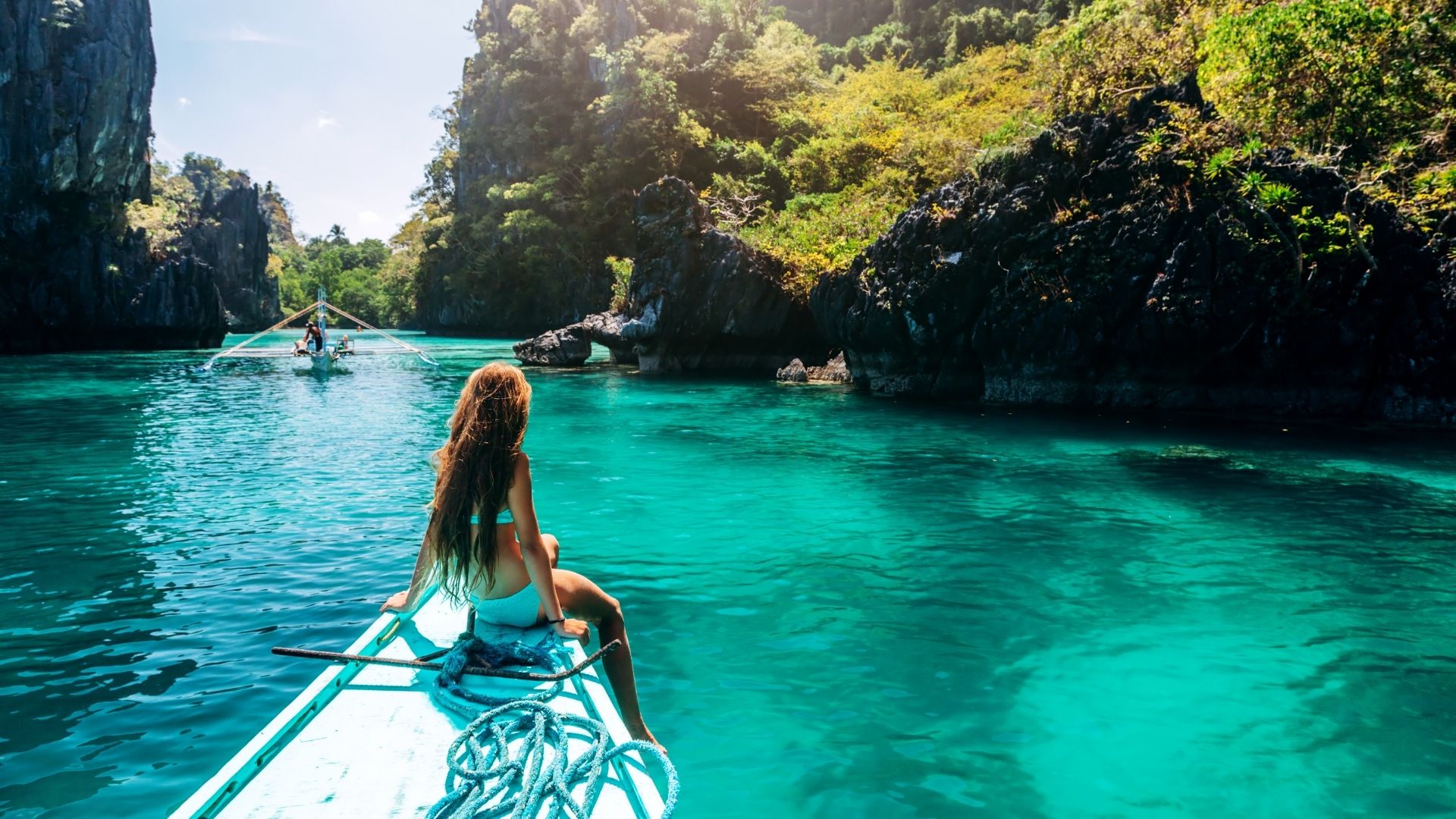 Viajante na proa de um barco bangka durante um island hopping numa lagoa de El Nido