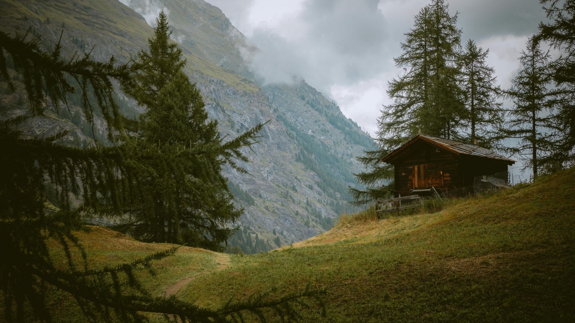 Um chalé de madeira num alpe suíço, aos pés de uma montanha na neblina