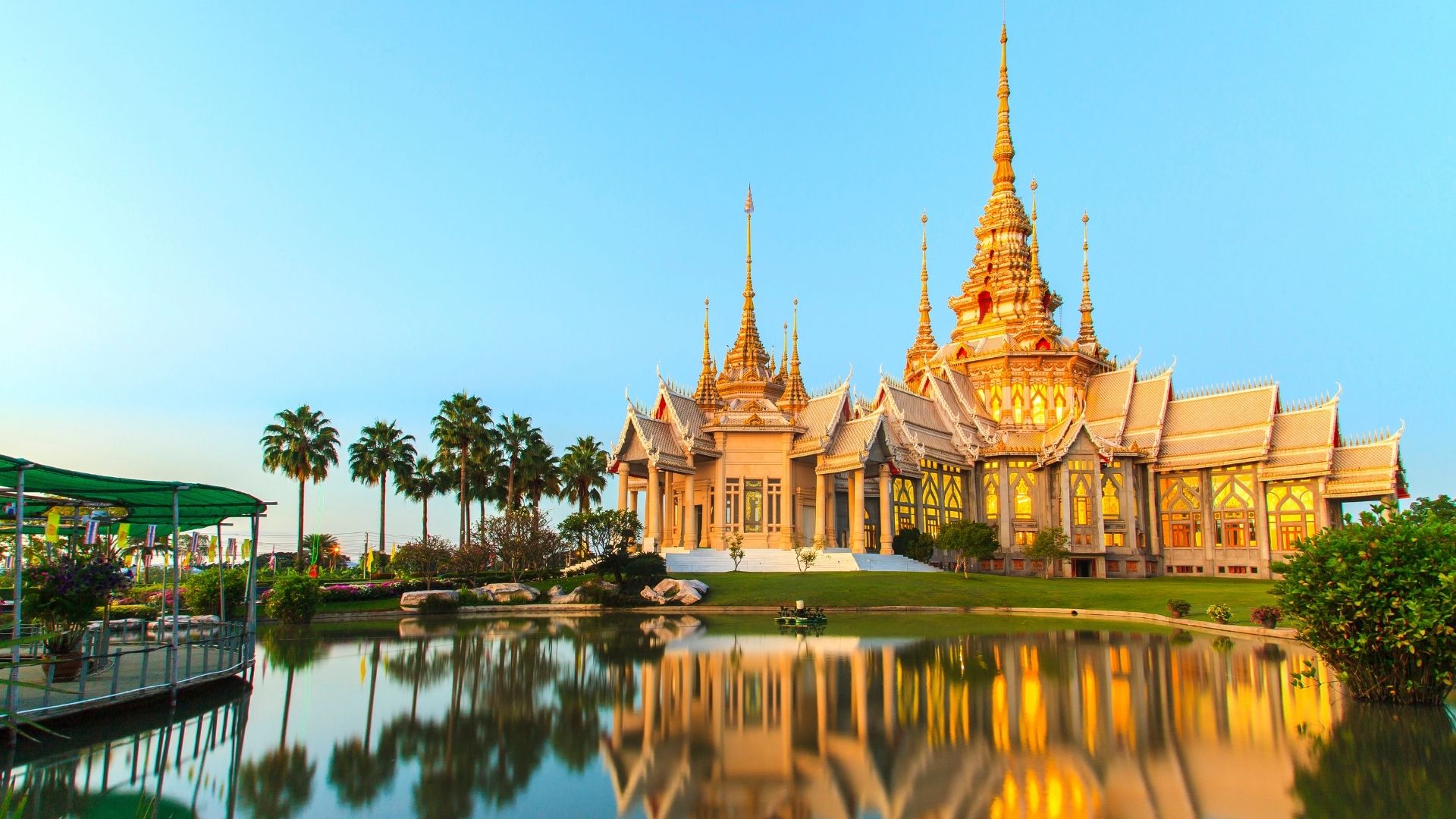 Un temple thaïlandais aux toits dorés se reflétant dans un bassin, en Thaïlande