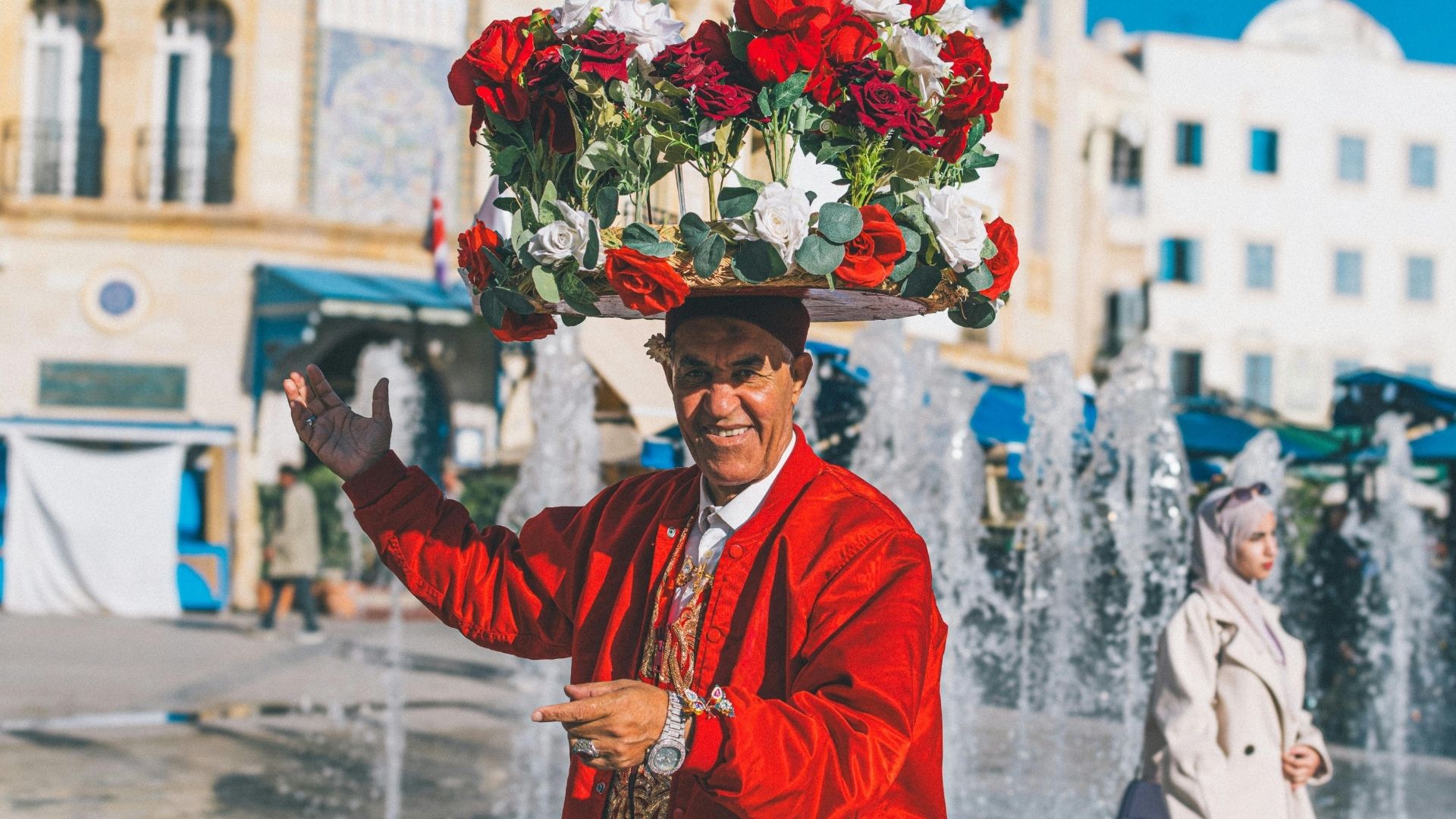 A flower seller in traditional red dress on a square in Tunis