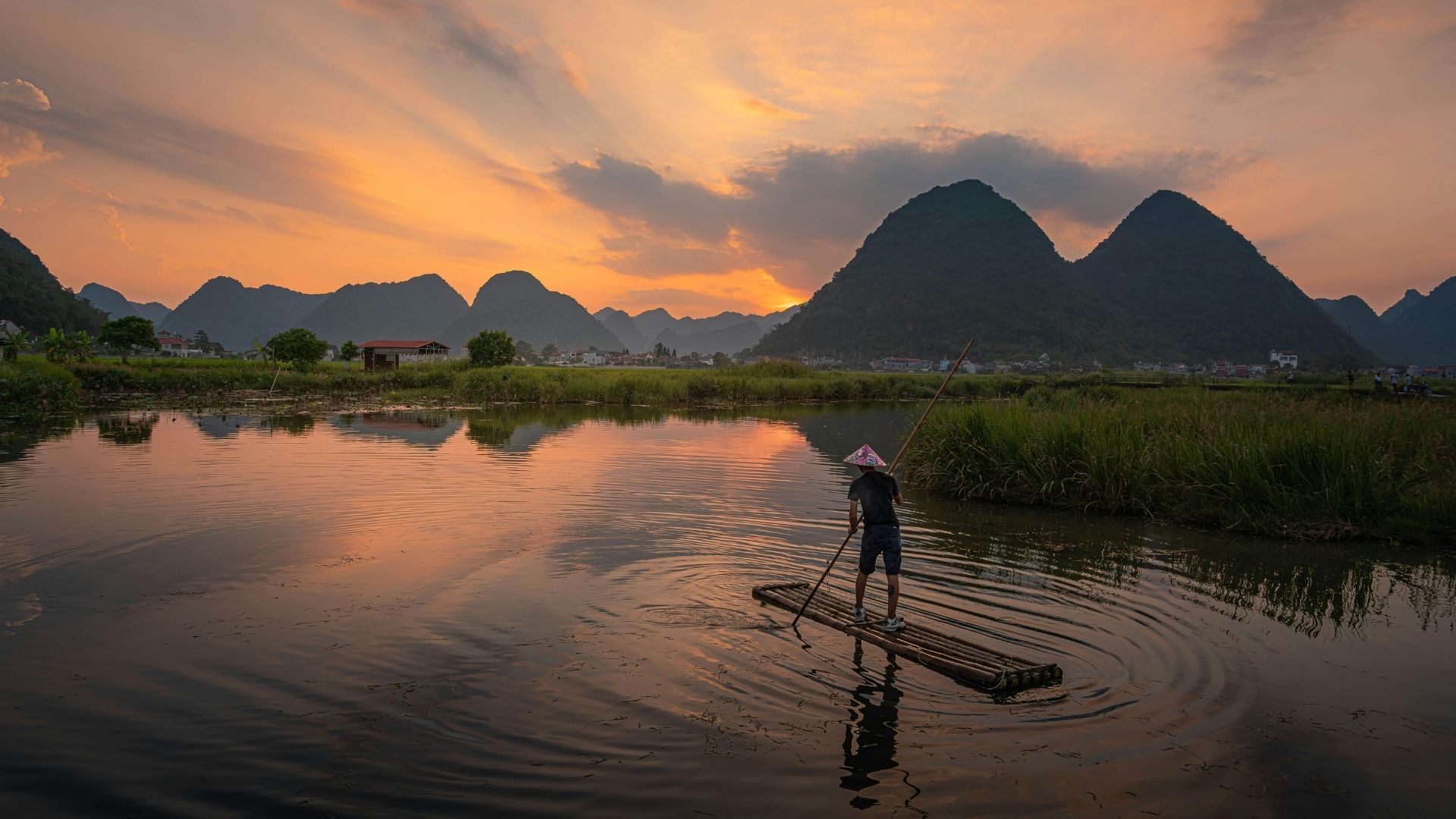 Coucher de soleil sur une rivière du Vietnam, un voyageur sur un radeau de bambou