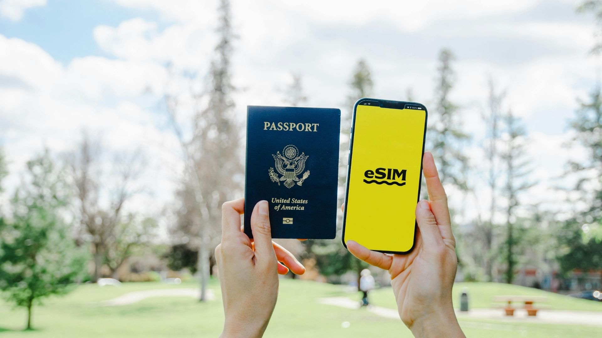 Um passaporte e um smartphone a mostrar eSIM, lado a lado ao ar livre